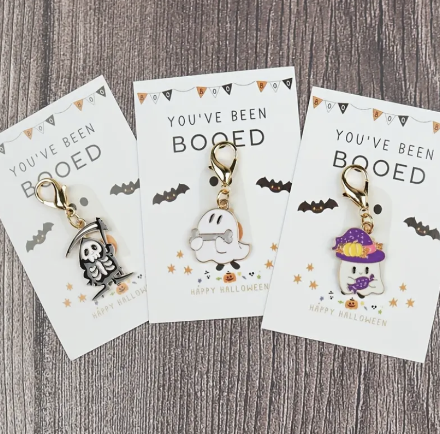 Three Halloween-themed keychains on cards with 'You've Been Booped' text on a wooden surface.