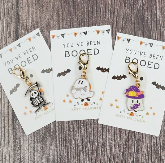 Three Halloween-themed keychains on cards with 'You've Been Booped' text on a wooden surface.