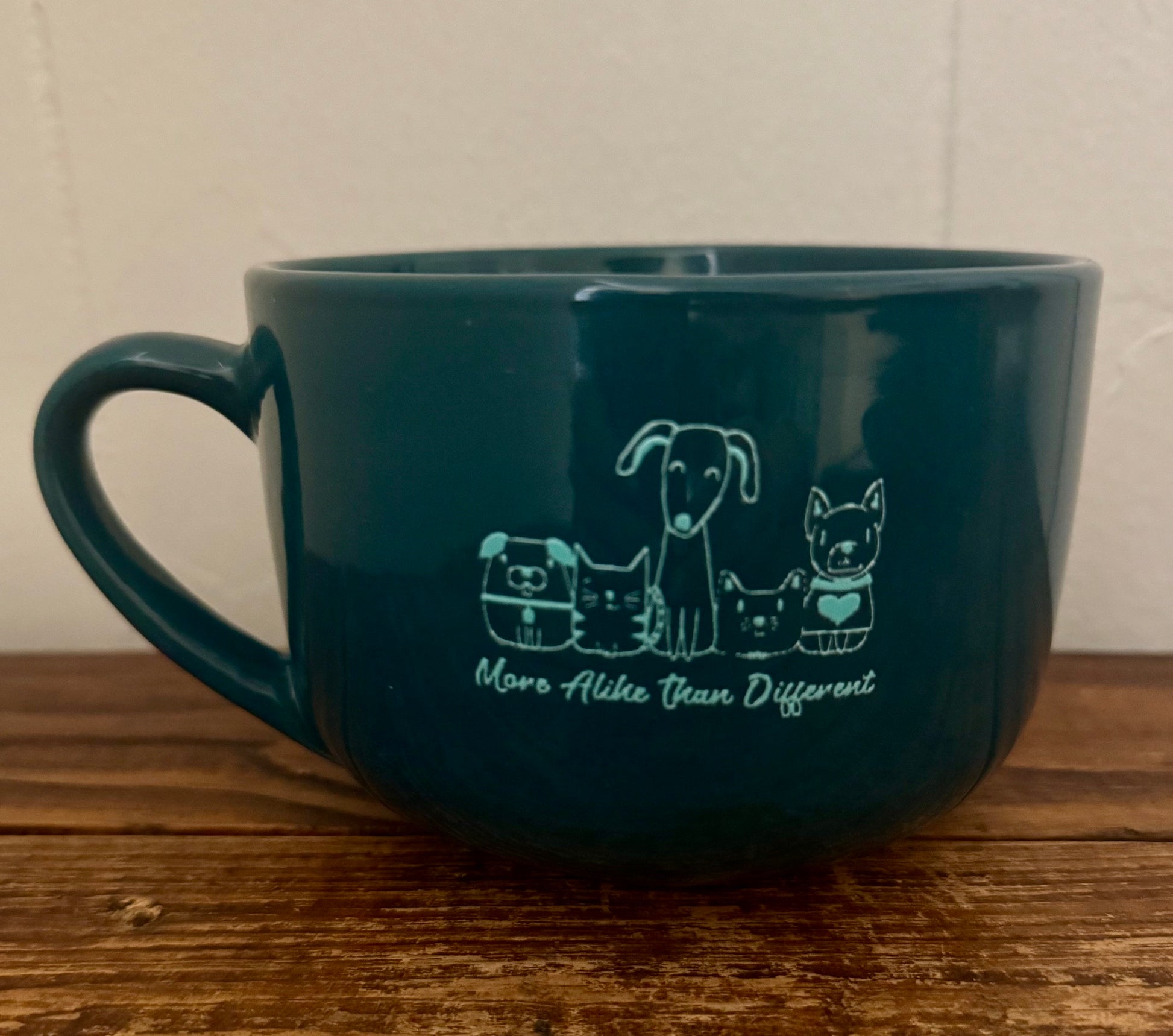 Large ceramic mug with illustrations of cats and dogs and the phrase More Alike Than Different