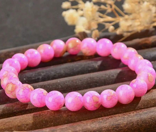 Pink beaded bracelet on a wooden surface with blurred background