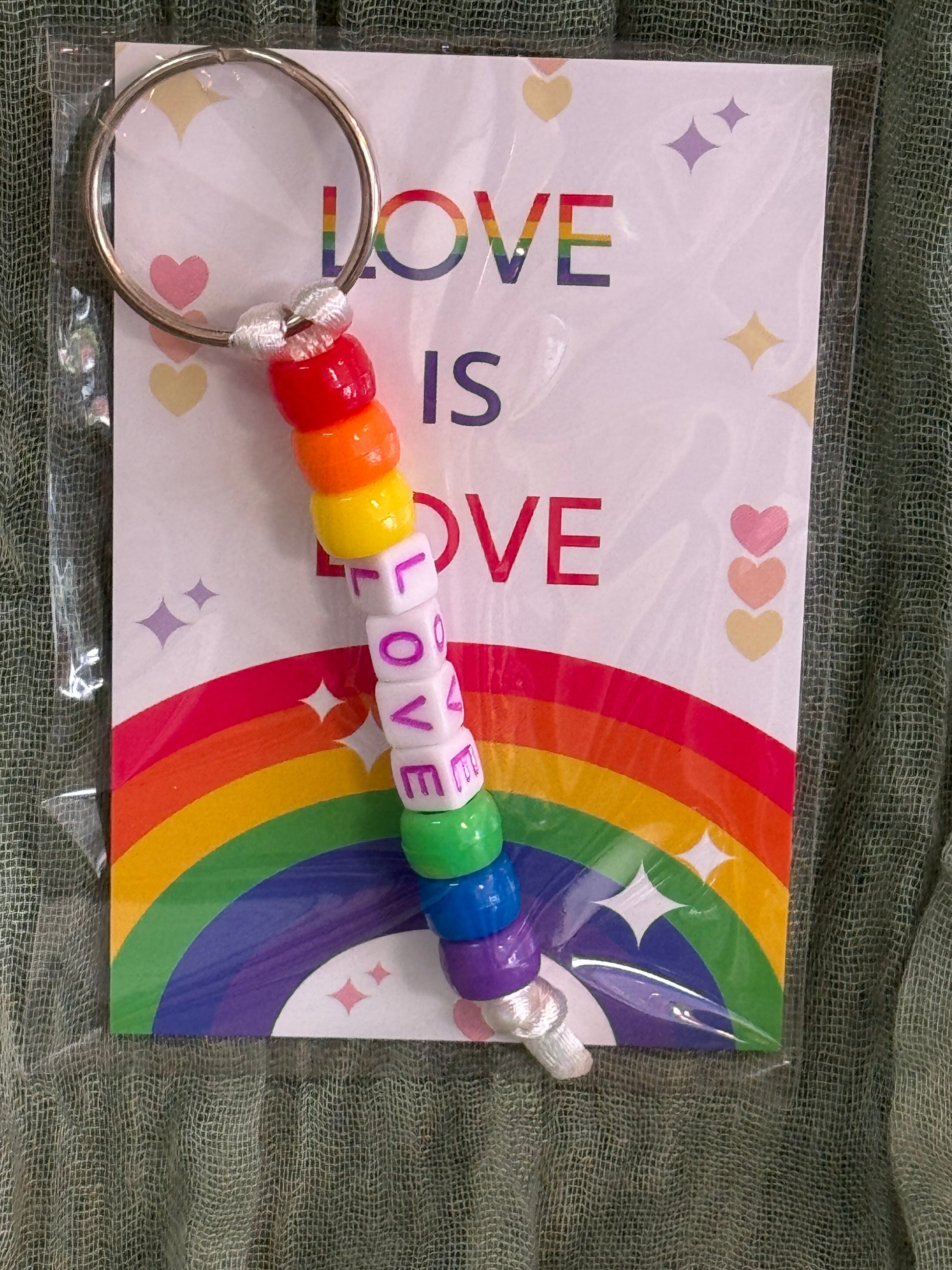 Beaded rainbow Pride keychain with word bead charms like Pride and Love on a Love is Love card