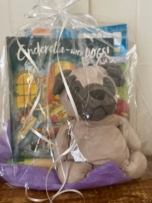 Plush pug dog toy with a children's book inside clear cellophane packaging.