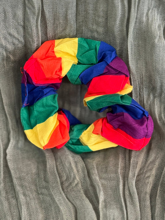 Bright rainbow-colored hair scrunchies stacked together in a soft, stretchy fabric