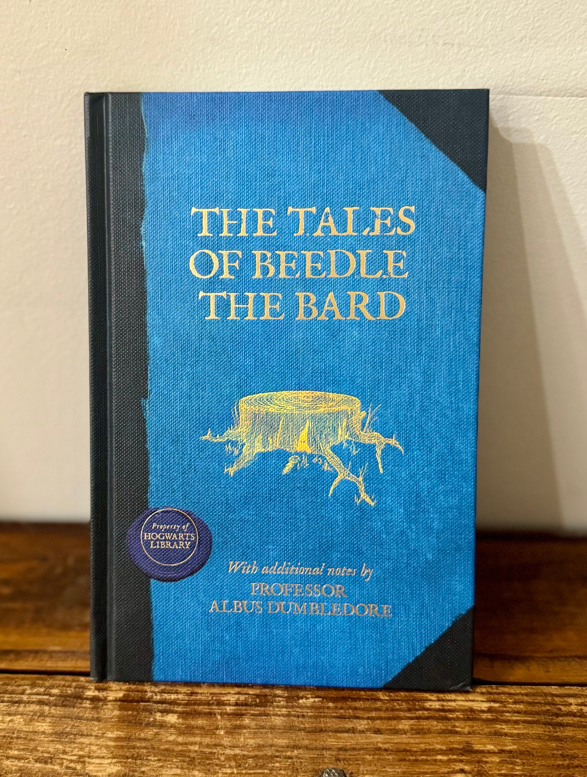 Cover of The Tales of Beedle the Bard by J.K. Rowling, showcasing an elegant and whimsical design, with an embossed illustration of a magical storybook surrounded by enchanting details.