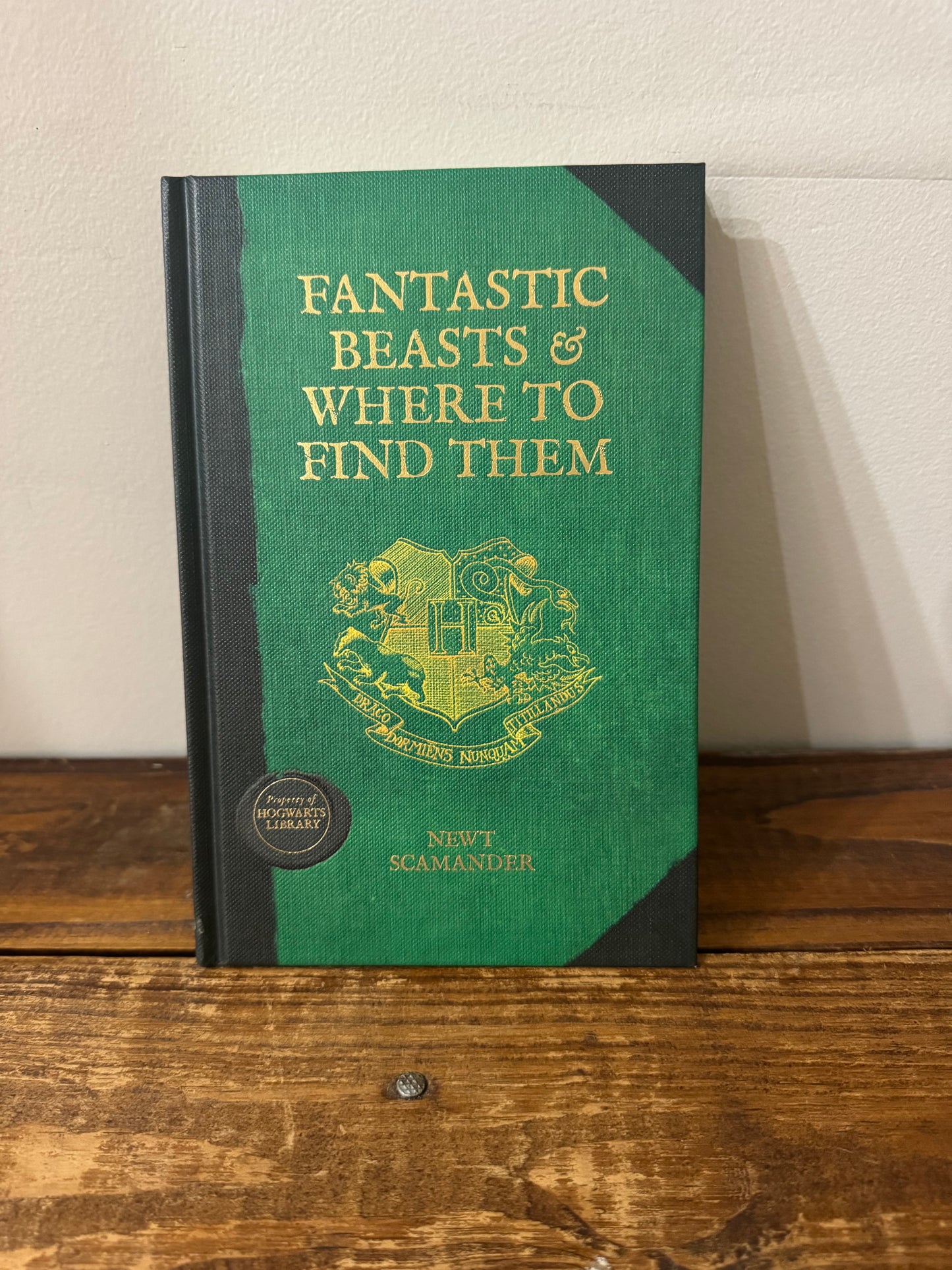 Cover of Fantastic Beasts and Where to Find Them by J.K. Rowling, featuring a detailed, vintage-style design with gold lettering and an intricate border, resembling a magical textbook from the wizarding world.