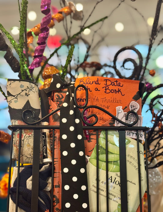 Decorative items including a polka dot ribbon, Halloween-themed books, and a black metal gate against a blurred background.