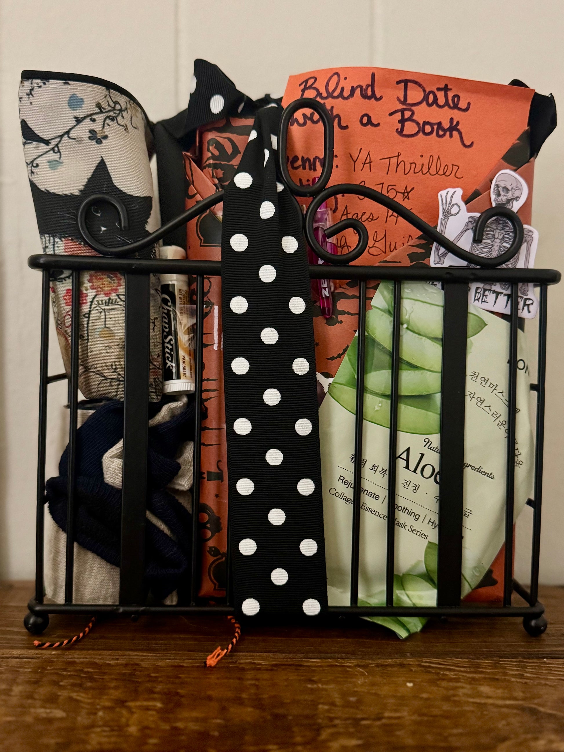Black metal book holder with books of various sizes and colors on a wooden surface.