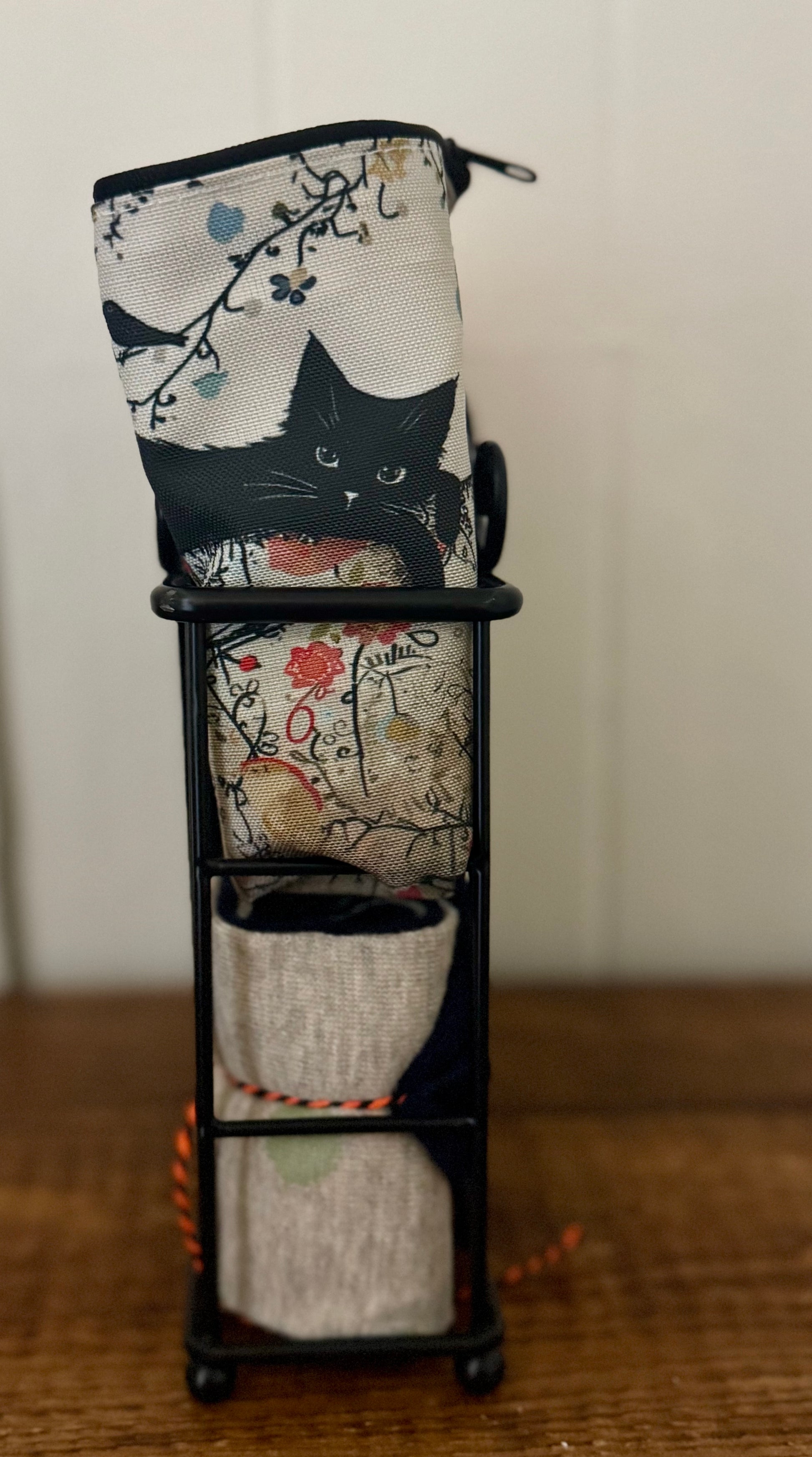 Makeup bag with a cat design in a stand on a wooden surface