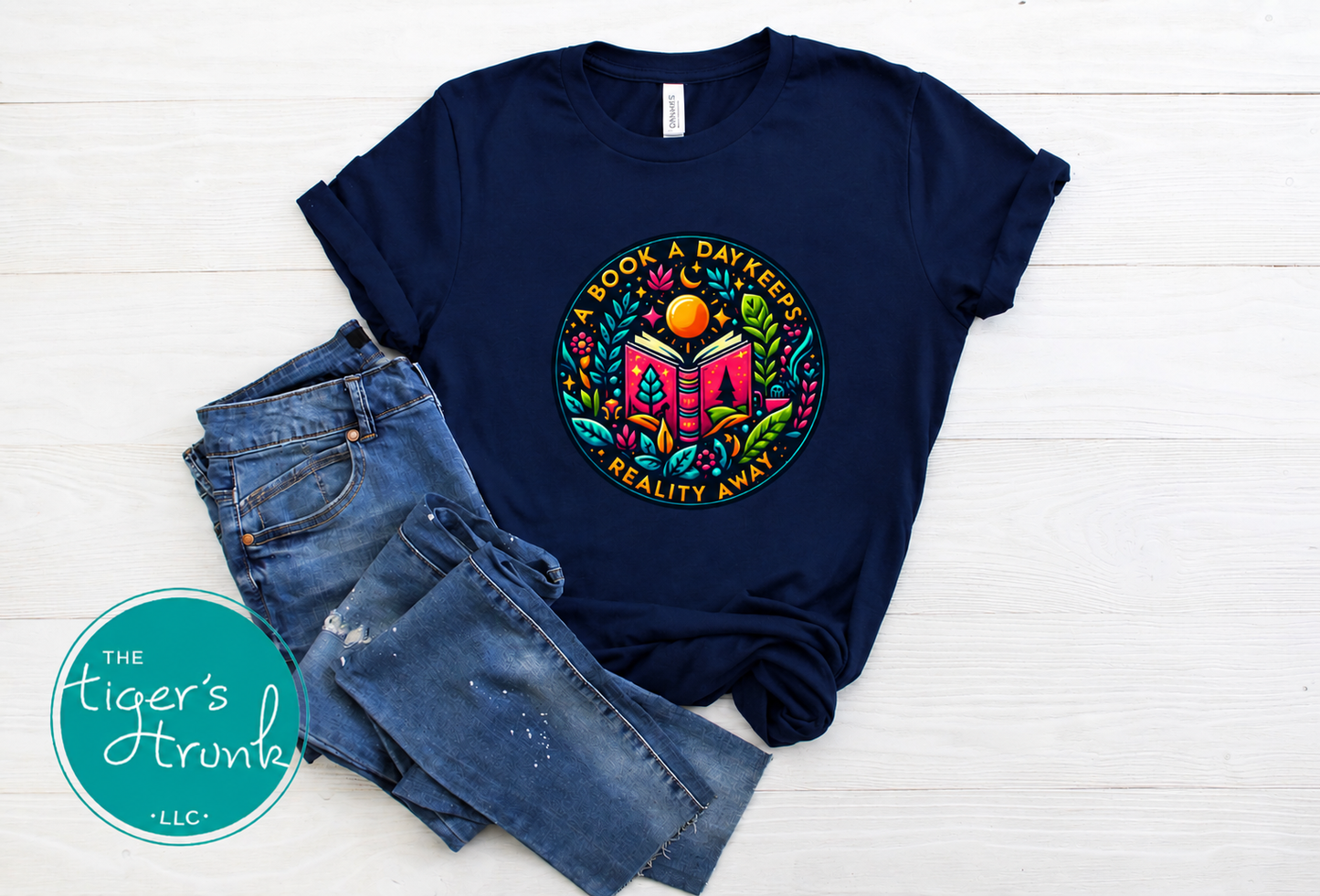 Navy short-sleeve T-shirt featuring a colorful circular graphic with an open book and the phrase "A Book a Day Keeps Reality Away."