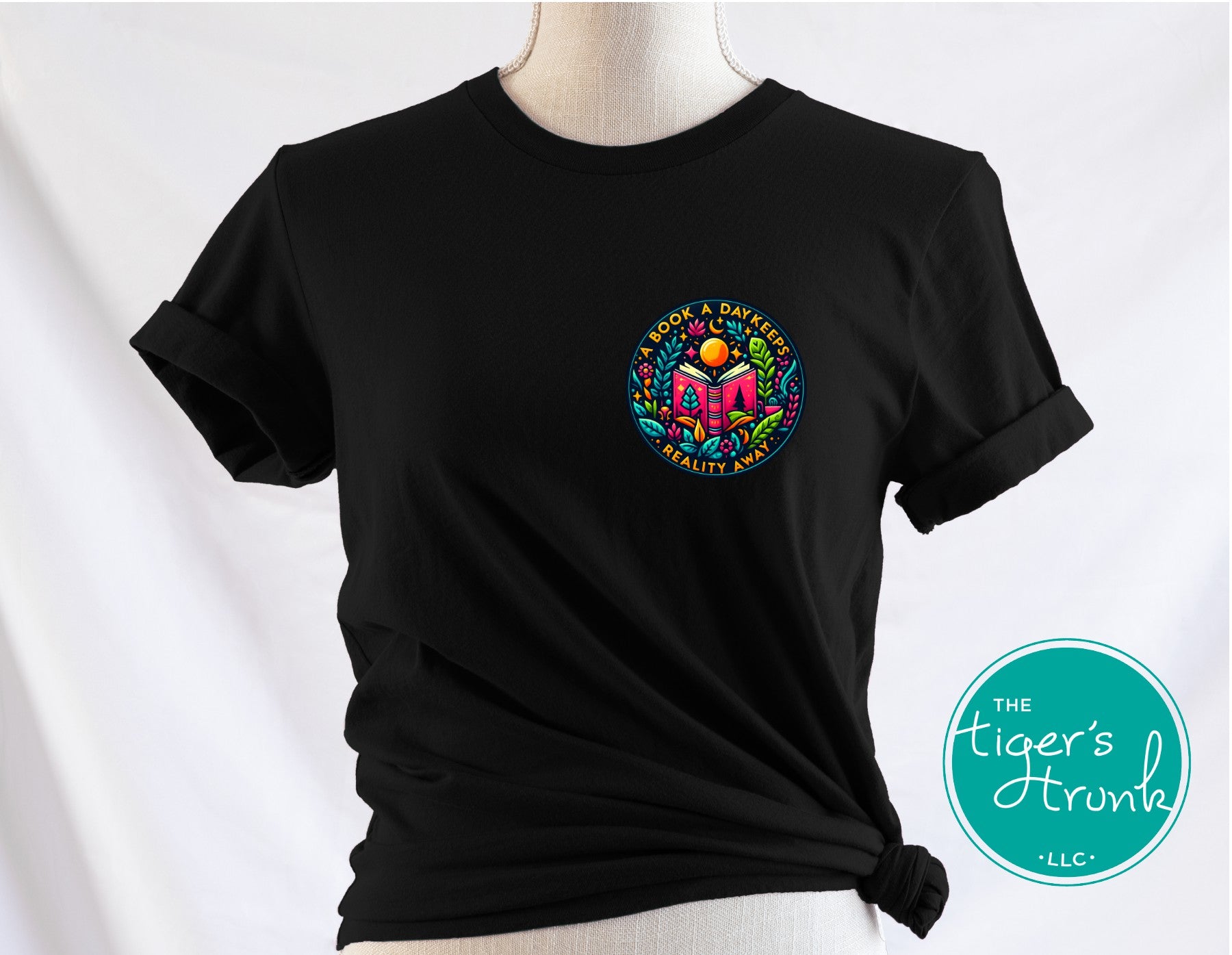 Black t-shirt with colorful graphic design on a mannequin against a white background, featuring 'The Tiger's Trunk LLC' logo.