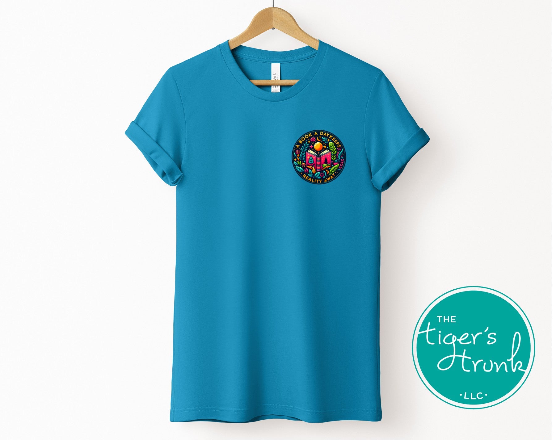 Blue t-shirt with a logo on a hanger, featuring 'The Tiger's Trunk LLC' brand.
