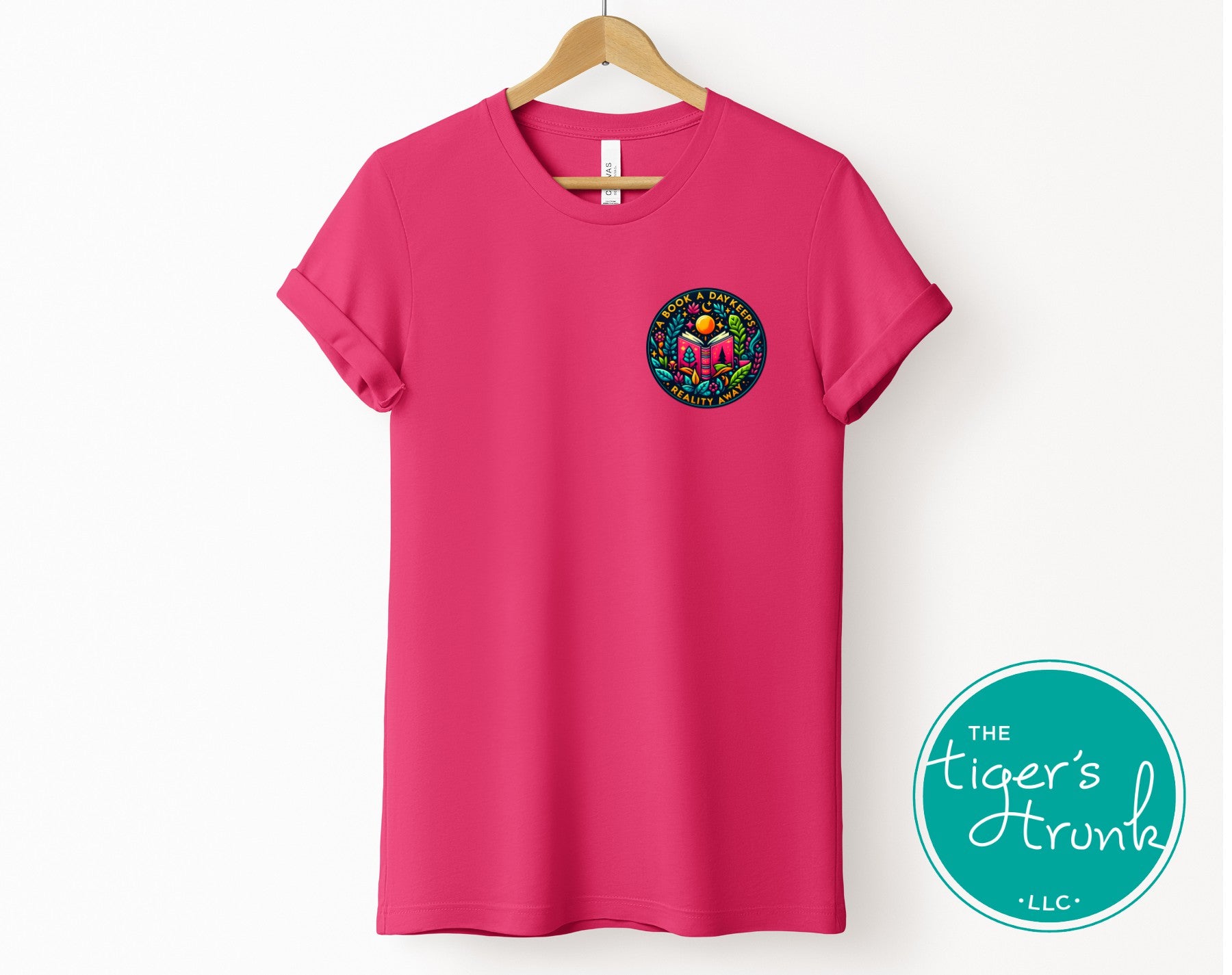 Pink t-shirt with a colorful logo on a hanger, featuring 'The Tiger's Trunk' brand.