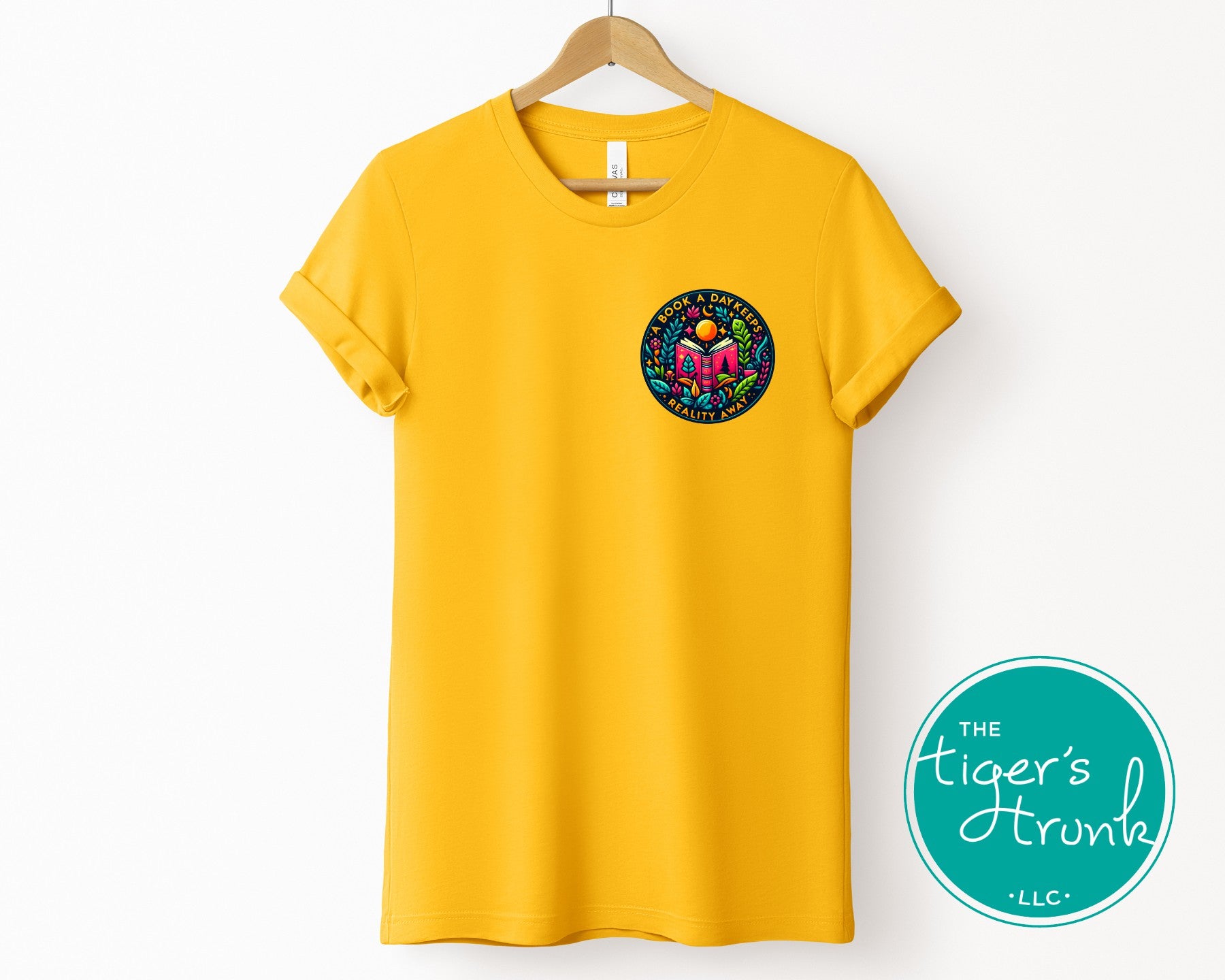 Yellow t-shirt with a colorful logo on a hanger, featuring 'The Tiger's Trunk' brand.