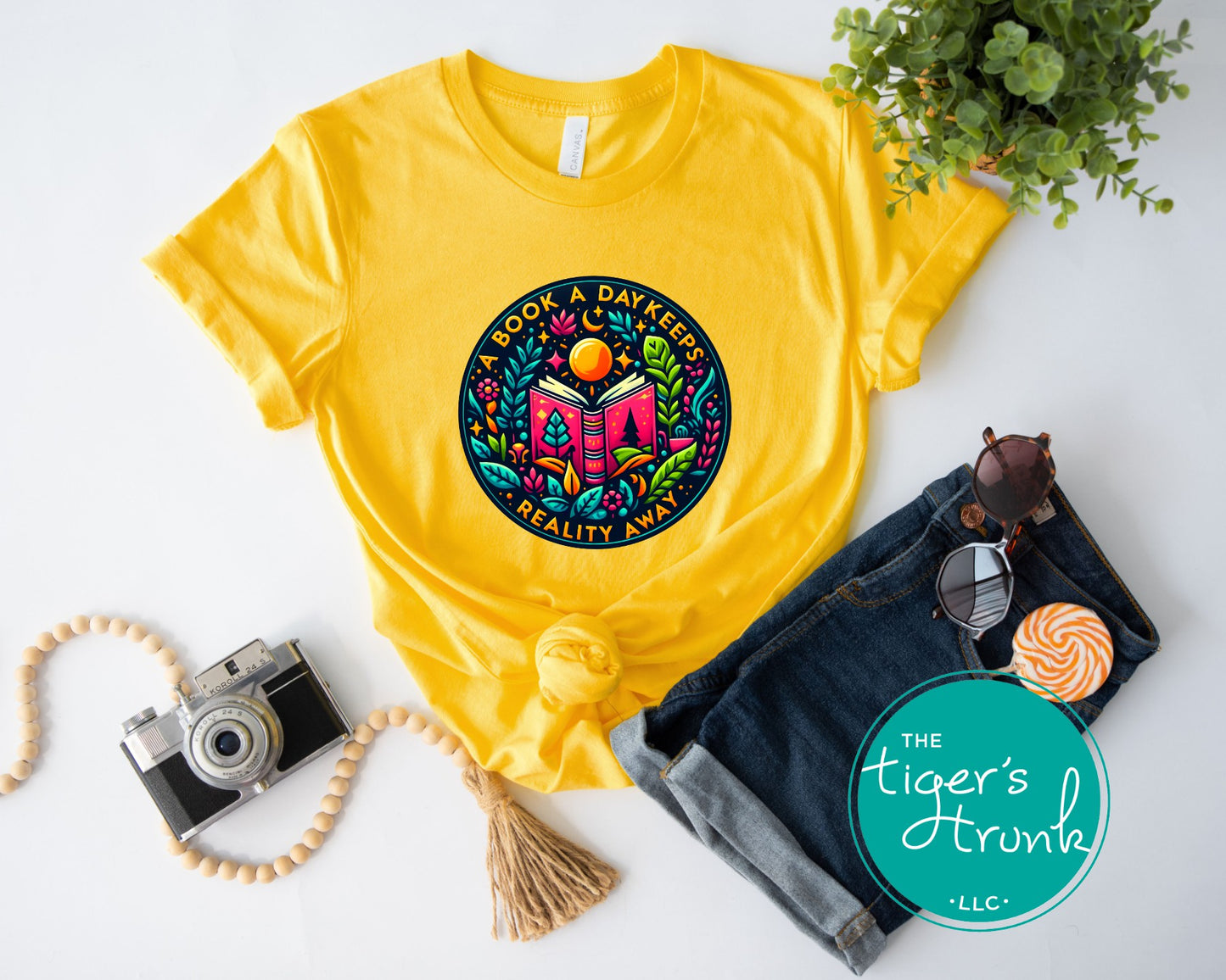 Yellow t-shirt with colorful graphic design on a white surface with accessories.
