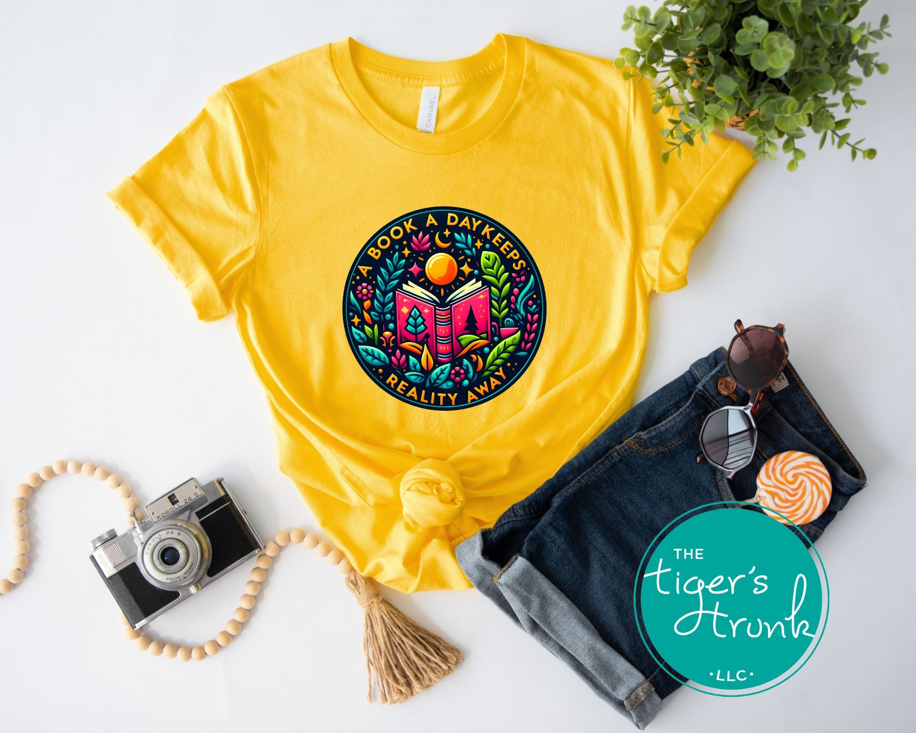 Yellow t-shirt with colorful graphic design on a white surface with accessories.