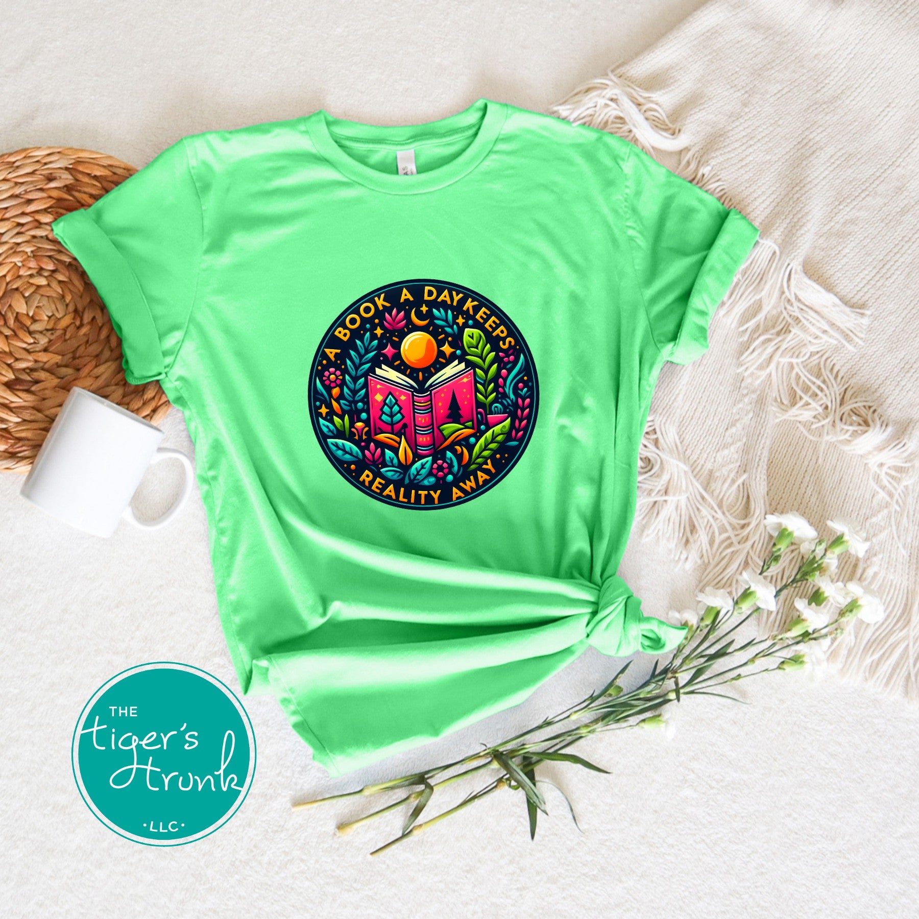 Green t-shirt with colorful graphic design on a textured surface with 'The Tiger's Trunk' logo.