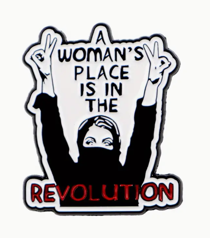 A Woman’s Place Is in the Revolution enamel pin with bold lettering, feminist empowerment accessory for jackets and bags