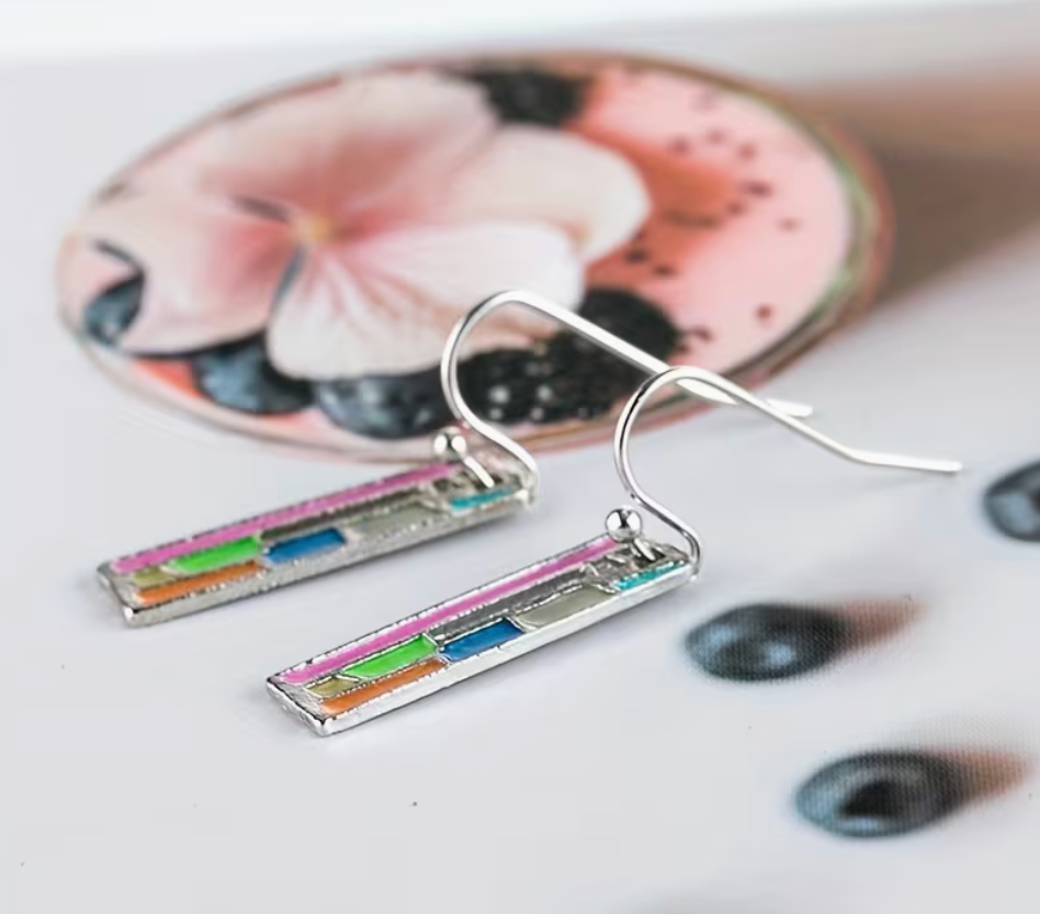 colorful abstract bookshelf earrings displayed on a flatlay with soft floral decor