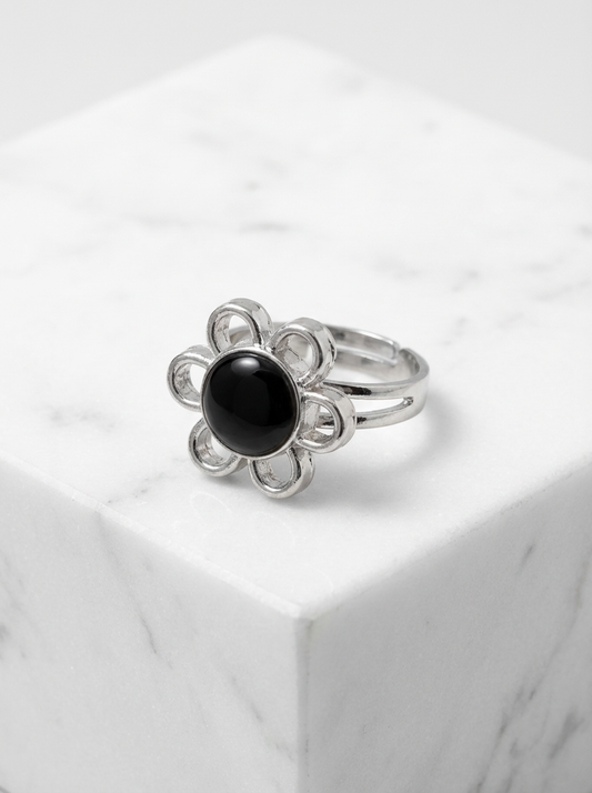 Adjustable silver tone flower mood ring with a color changing center displayed on a white marble surface