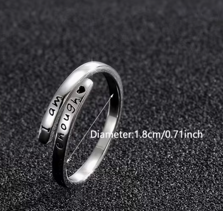 Adjustable silver tone affirmation ring engraved with the message I am enough showing inner diameter measurement on a dark textured background