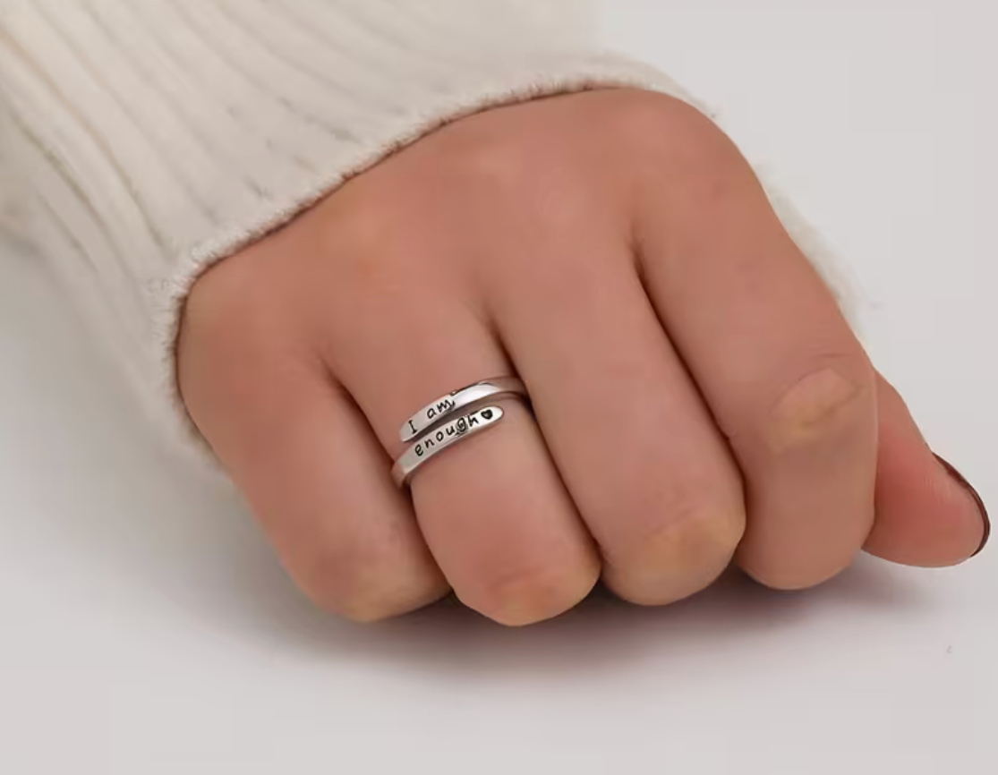 Adjustable silver tone affirmation ring engraved with the message I am enough worn on a hand for fit and scale reference