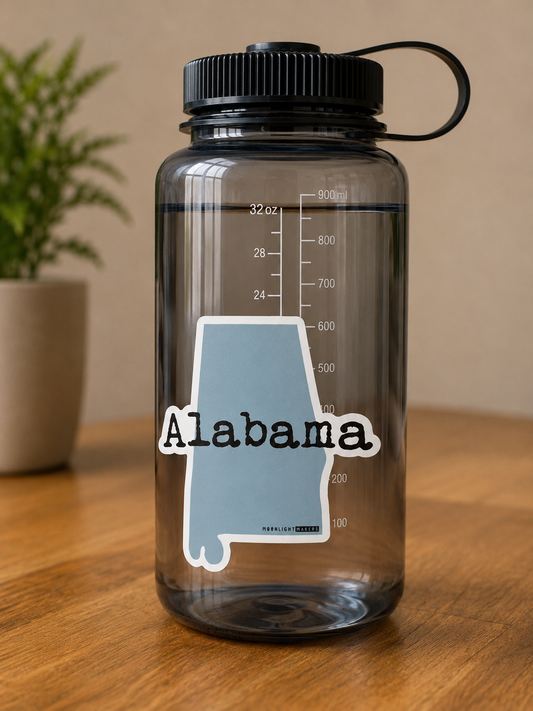 Light blue Alabama state-shaped vinyl sticker with Alabama written across the center displayed on a water bottle.