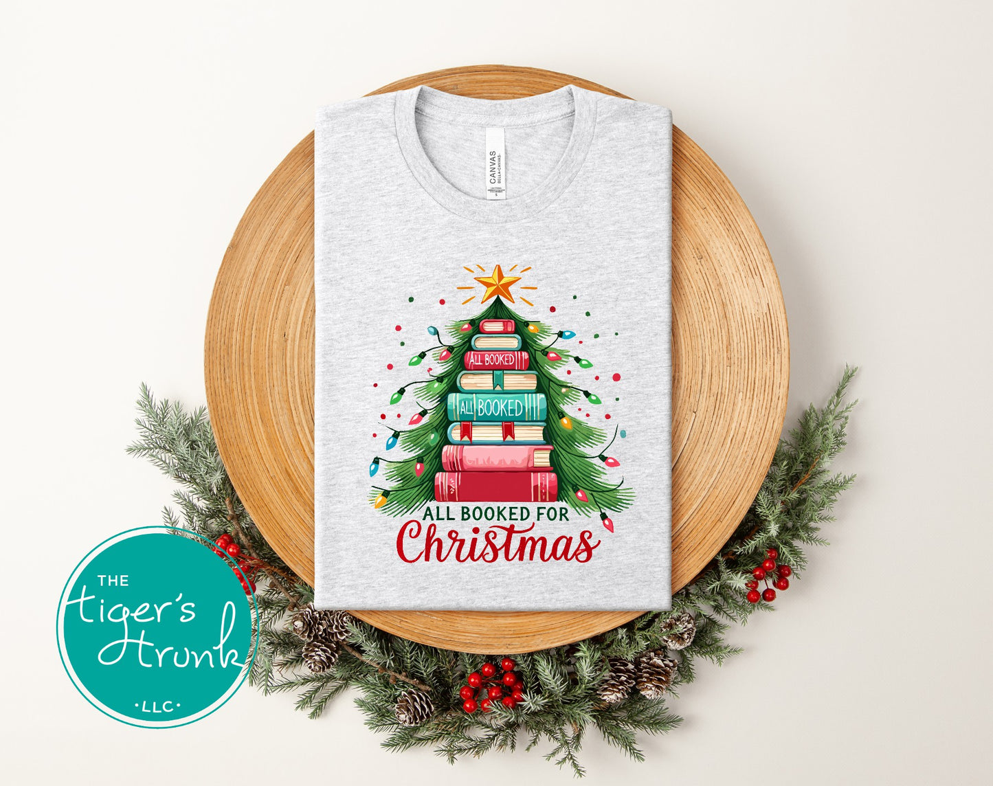 Ash gray short-sleeve shirt featuring a holiday book tree graphic with the phrase "All Booked for Christmas."