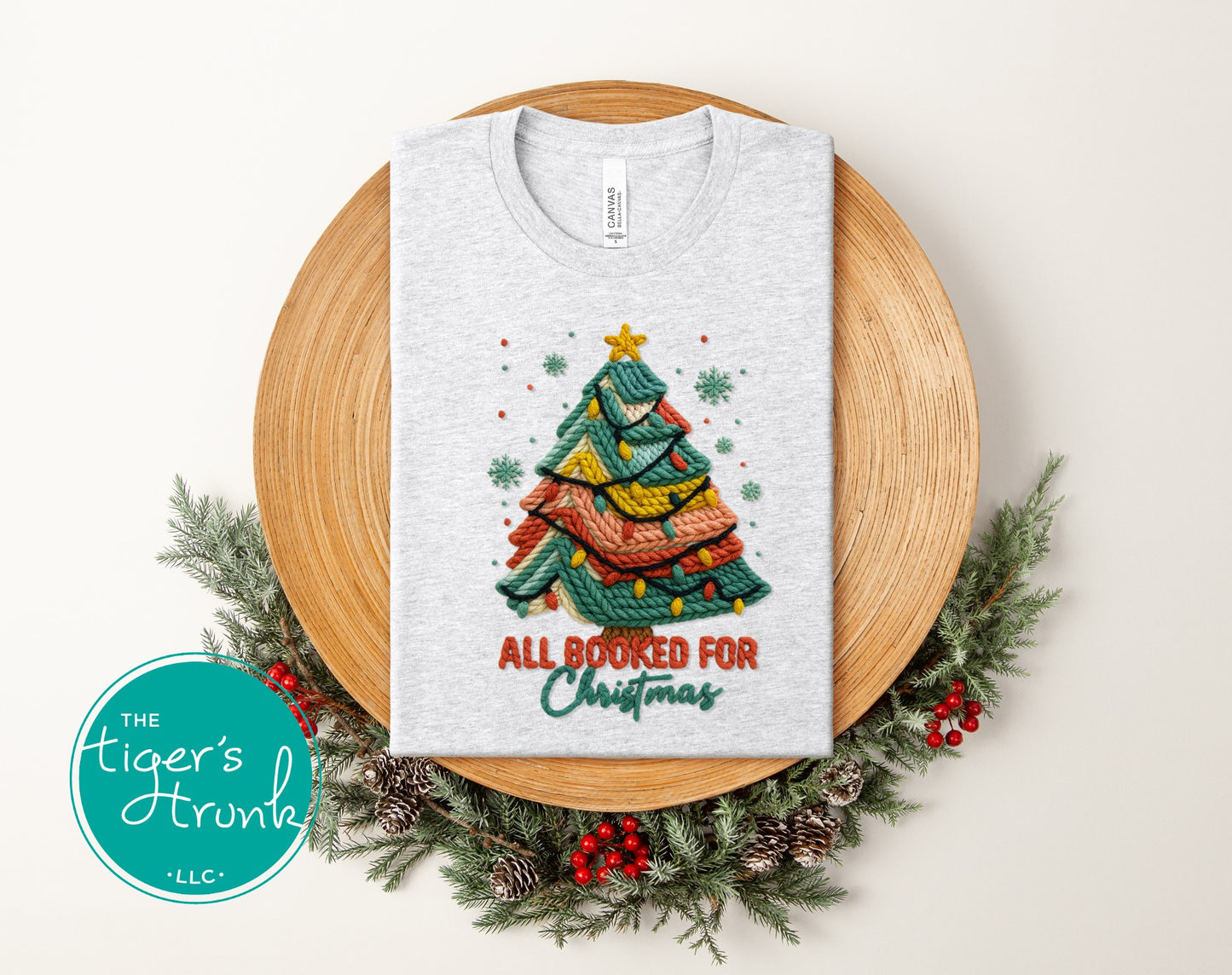 Ash gray short-sleeve shirt displaying a knitted Christmas tree graphic with the words "All Booked for Christmas."