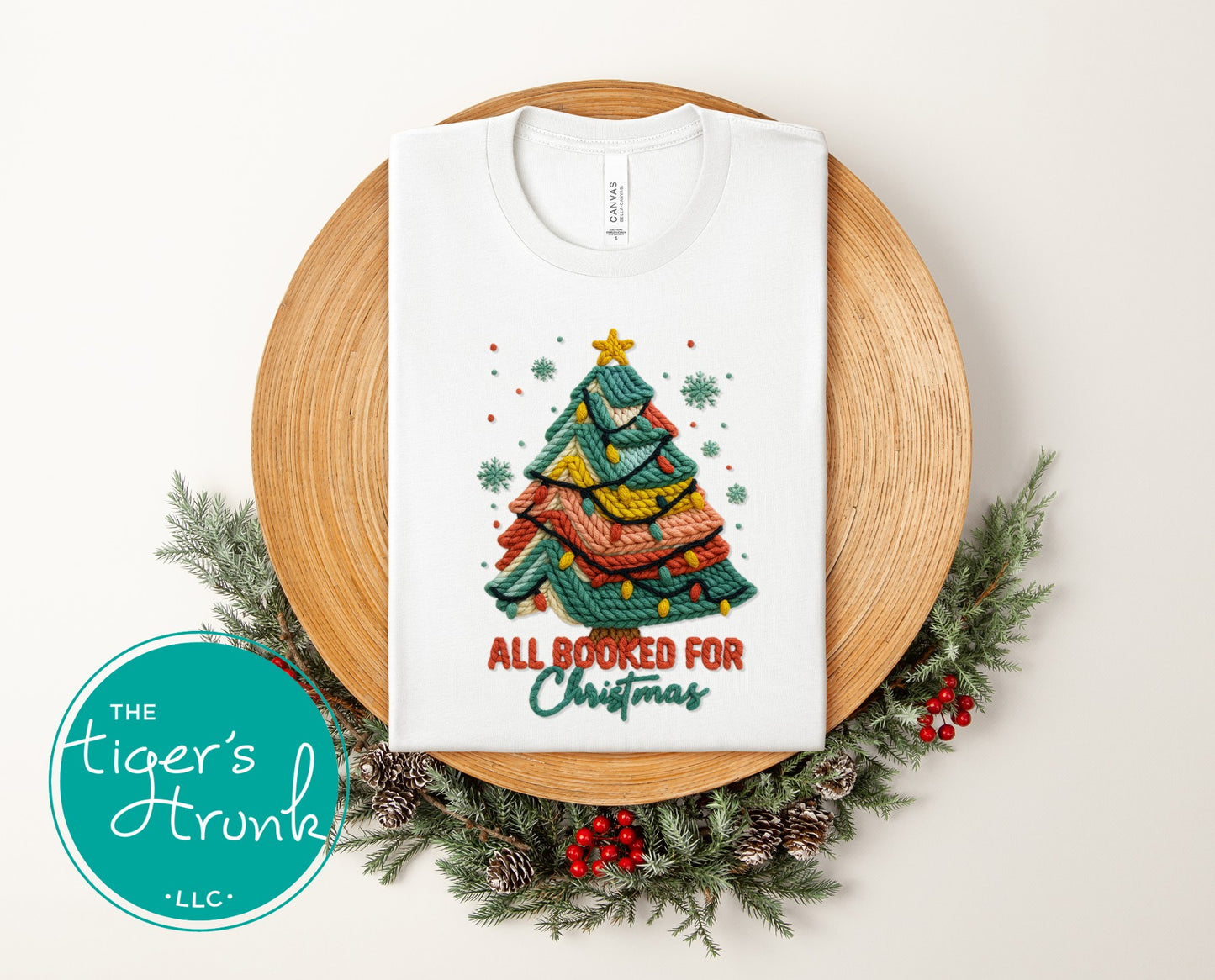 White short-sleeve shirt featuring a knitted-style Christmas tree with colorful lights and the phrase "All Booked for Christmas."