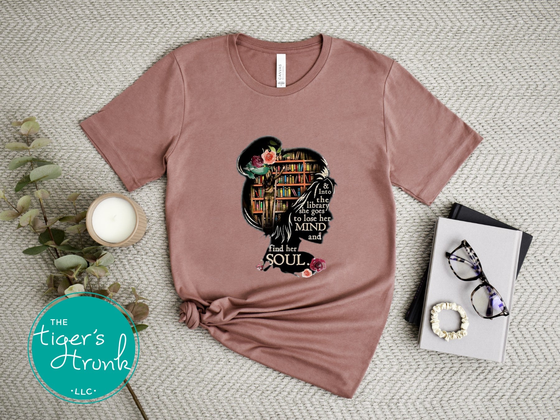 Mauve t-shirt with a graphic design on a textured surface with decor items.