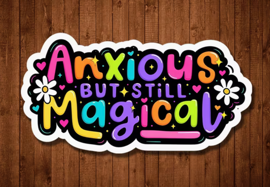 Colorful Anxious But Still Magical sticker displayed against rustic brown wood, featuring playful rainbow letters, white flowers, hearts, and sparkles.