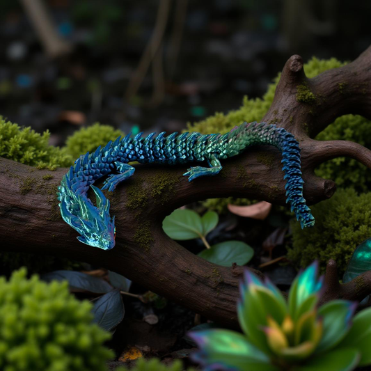 A blue and green articulated 3D printed dragon posed on a moss-covered tree branch in a lush forest setting.