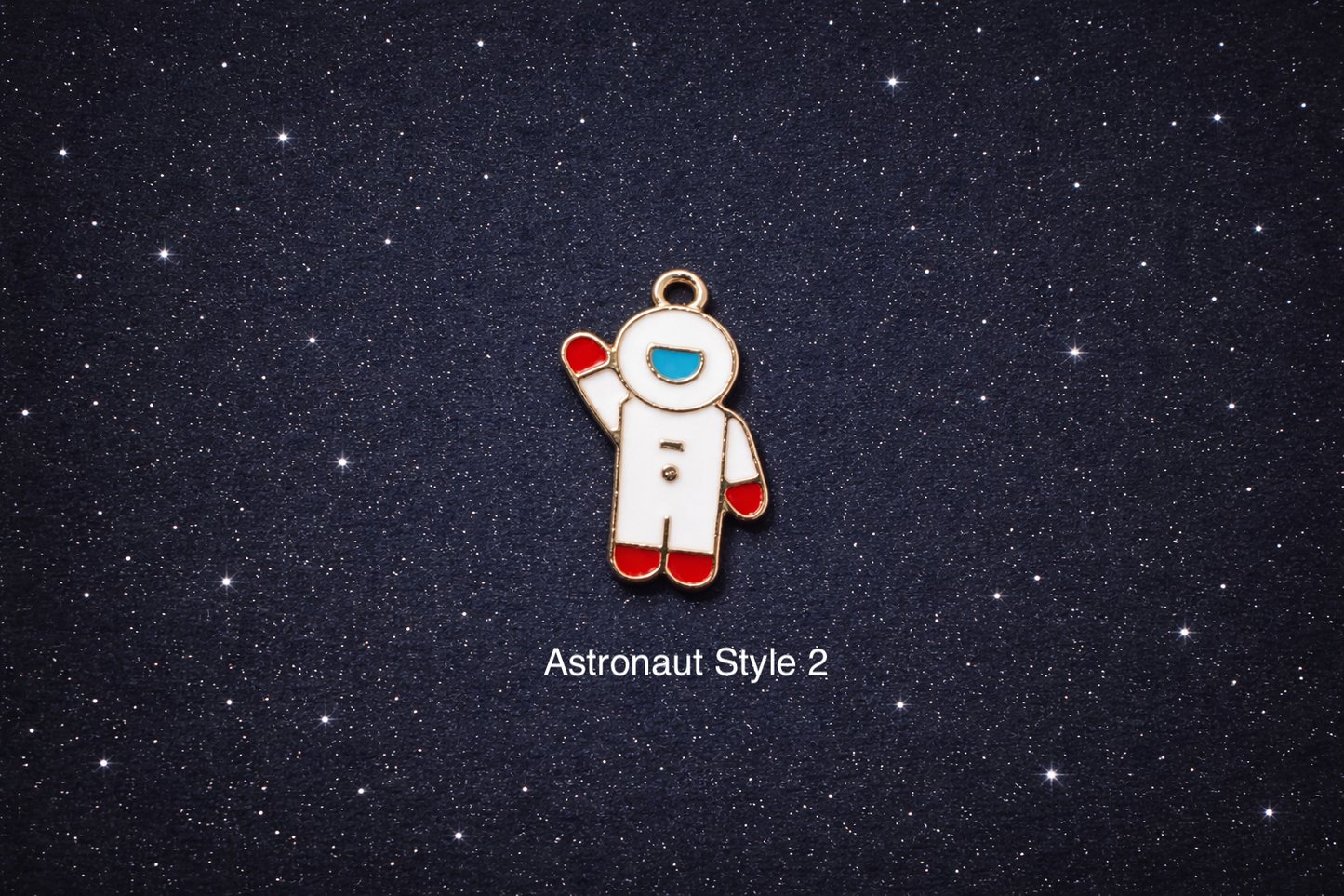 White and gold enamel astronaut charm with red gloves and boots and a blue visor, shown waving on a dark starry background and sold individually.