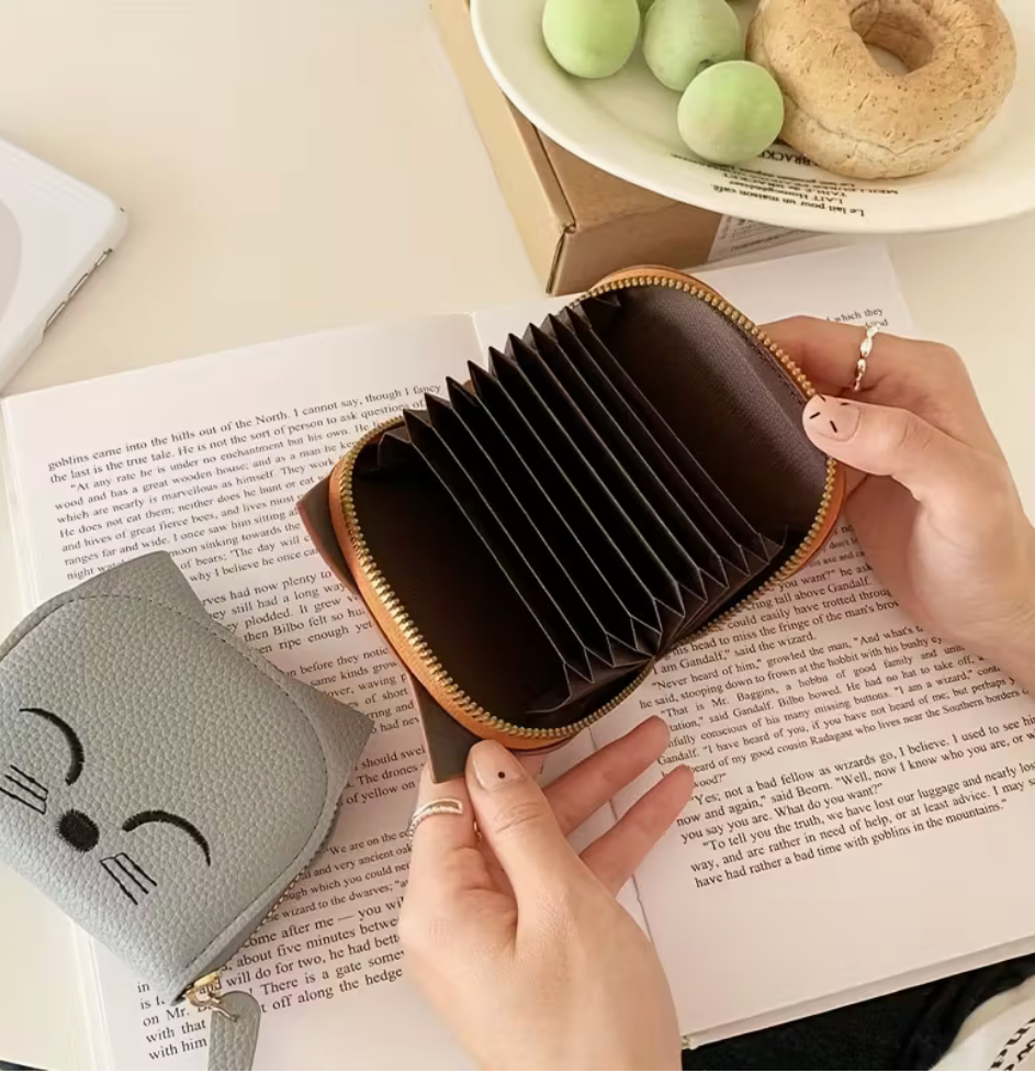 Interior accordion-style card holder of cat wallet shown open on a book