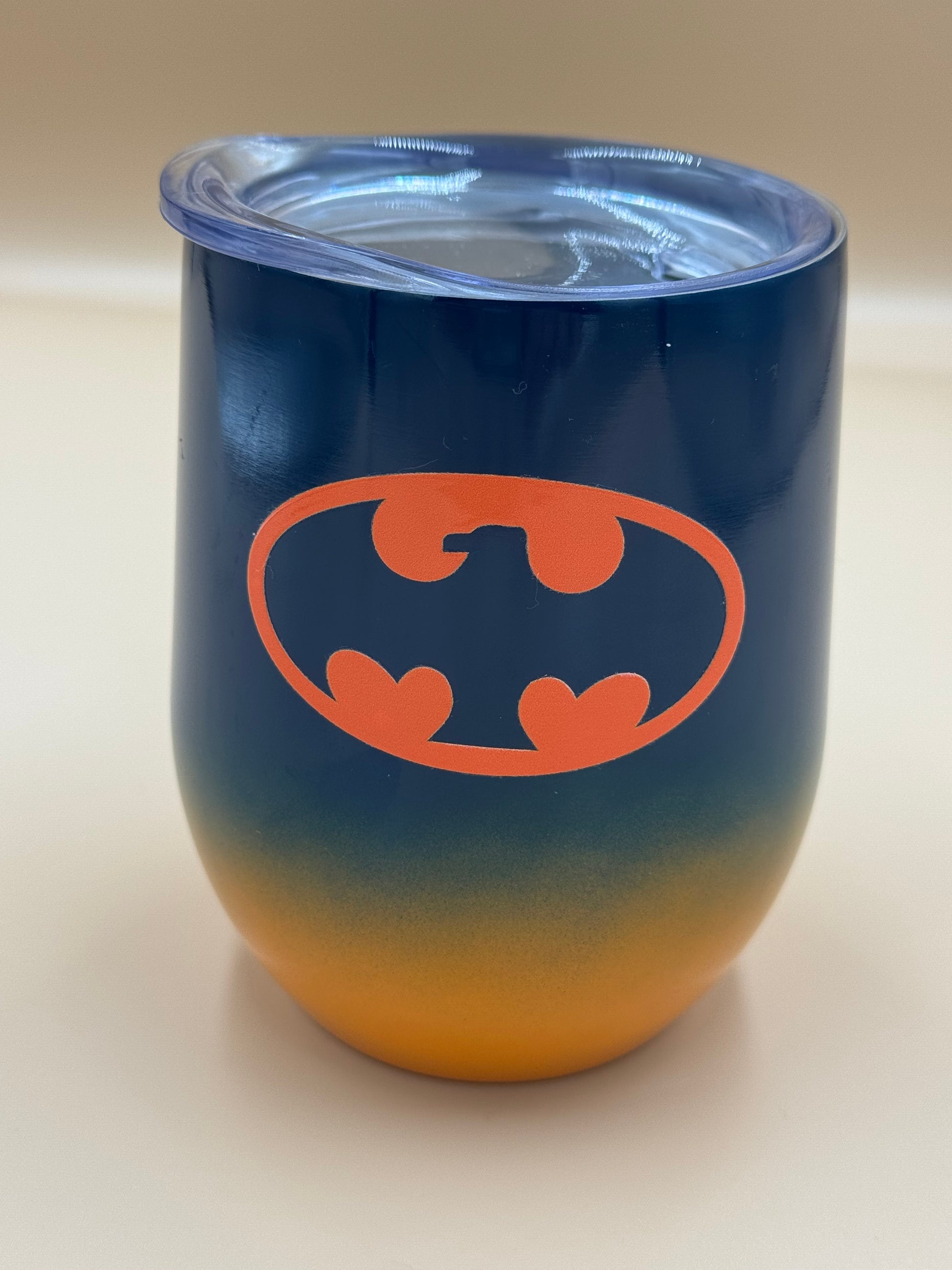 Blue and orange tumbler with orange bat symbol on a beige background