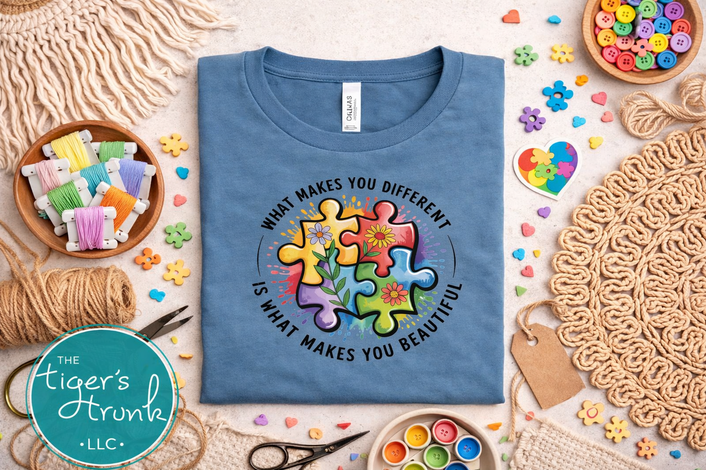 Blue t-shirt with colorful puzzle design and text on a table with craft supplies