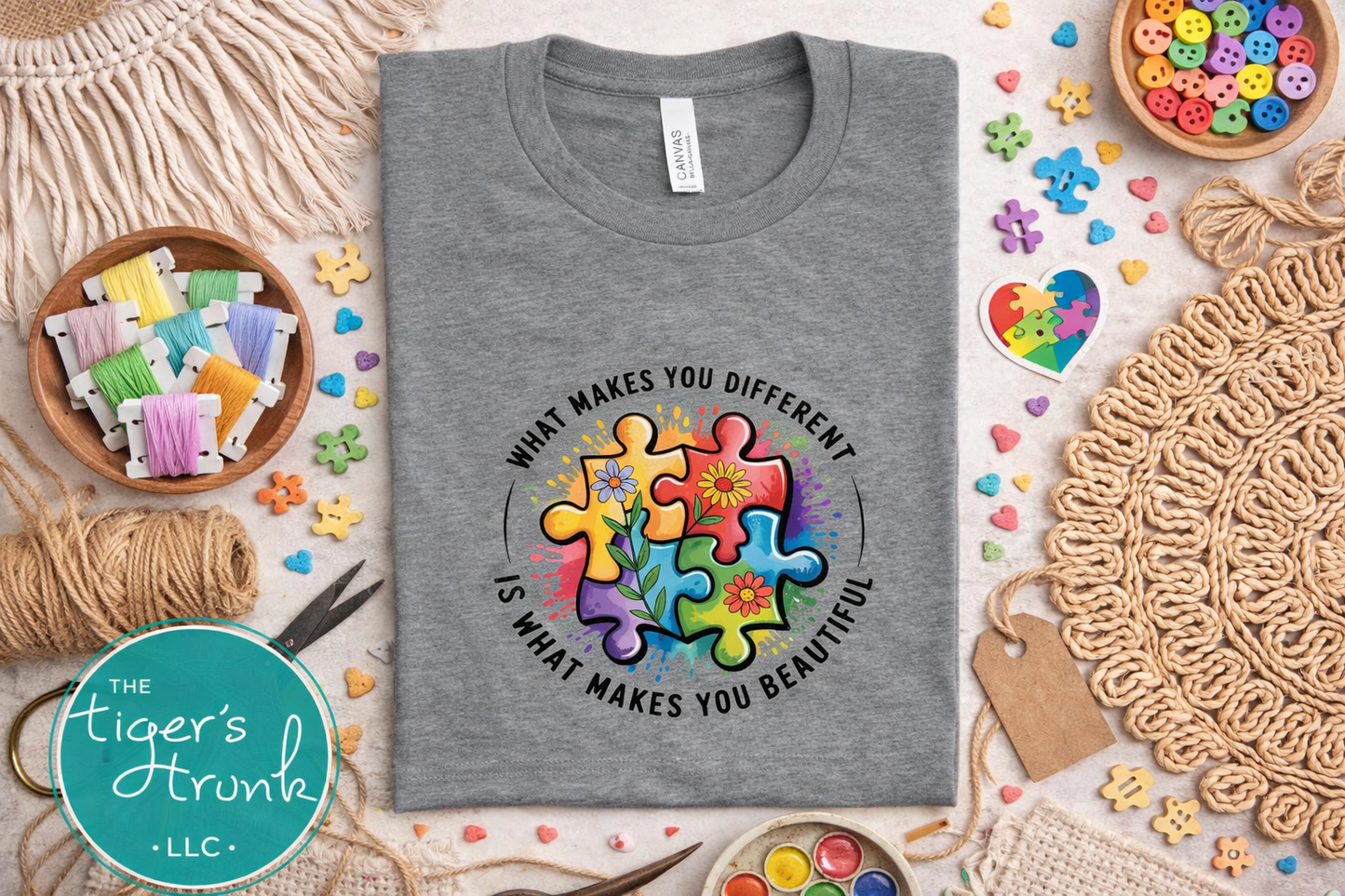 Gray t-shirt with colorful puzzle design and text on a table with craft supplies