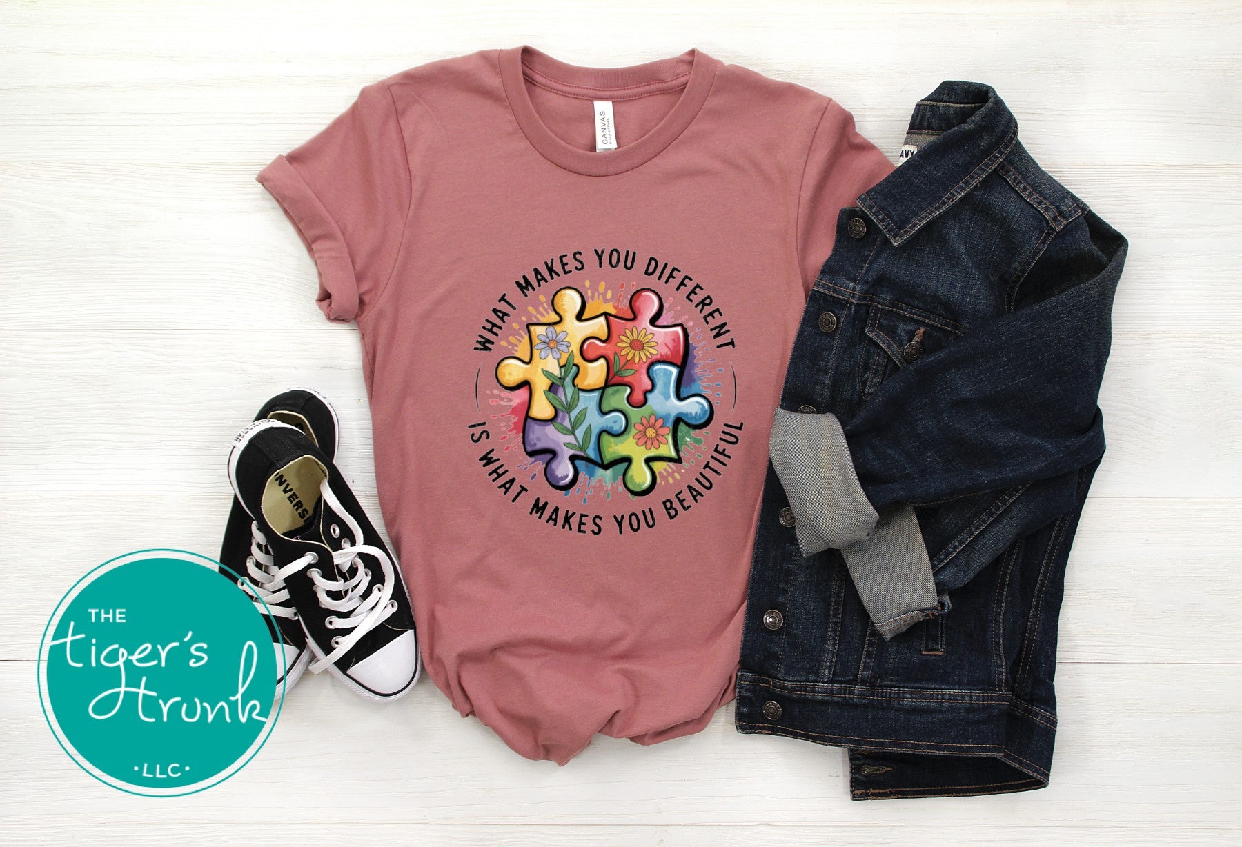 Pink t-shirt with colorful puzzle design and text, paired with denim jacket and sneakers on a white background.