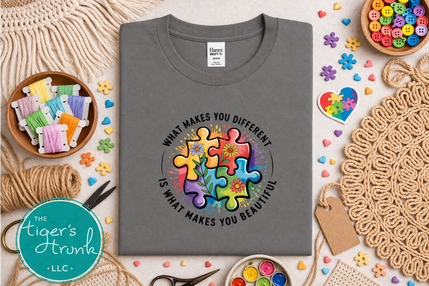 Gray t-shirt with colorful puzzle design and text on a table with craft supplies.