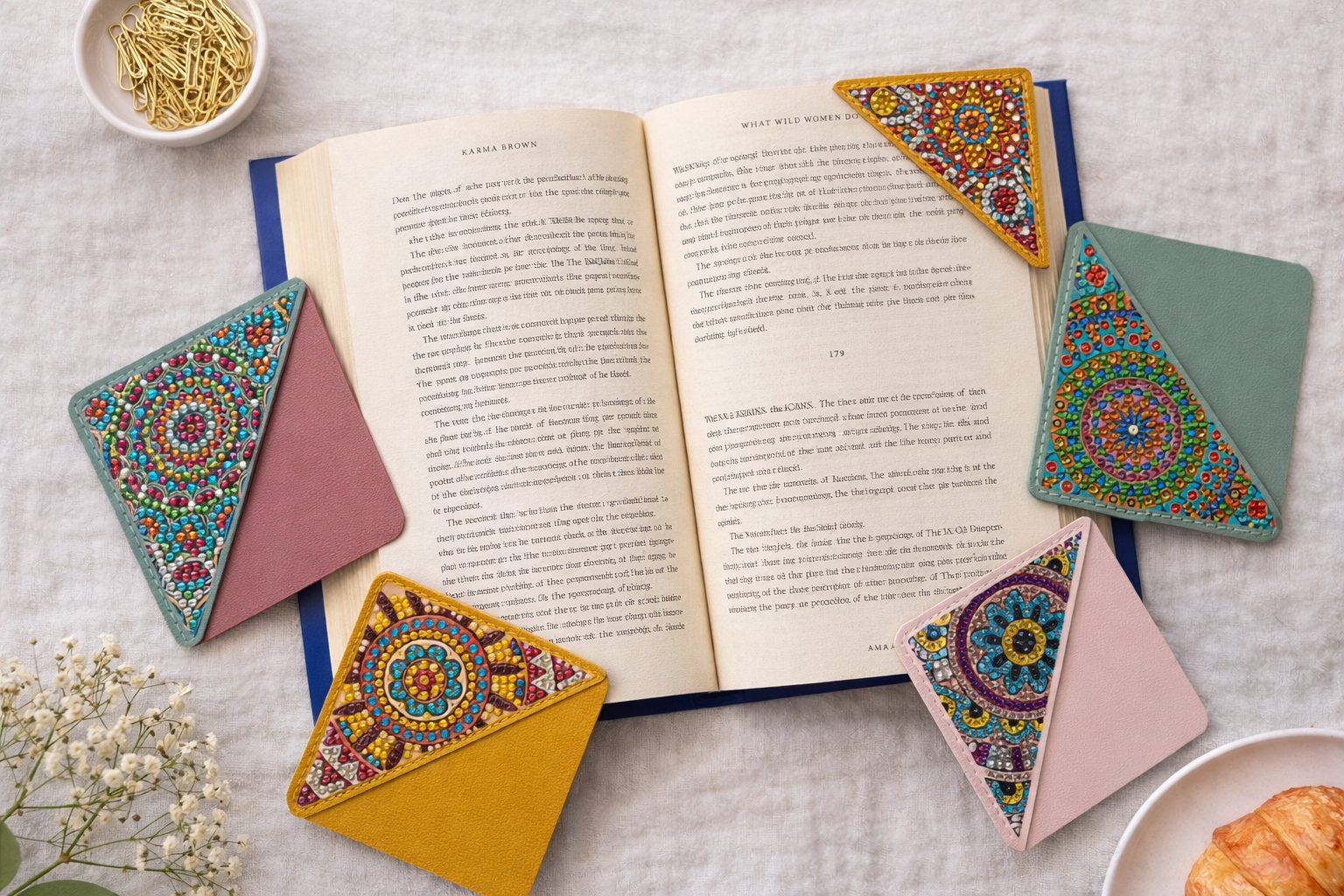 Assorted bejeweled vegan leather corner bookmarks in multiple colors styled around an open book