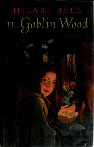Book cover of 'The Goblin Wood' by Hilari Bell with a person holding a book in a dark forest setting.