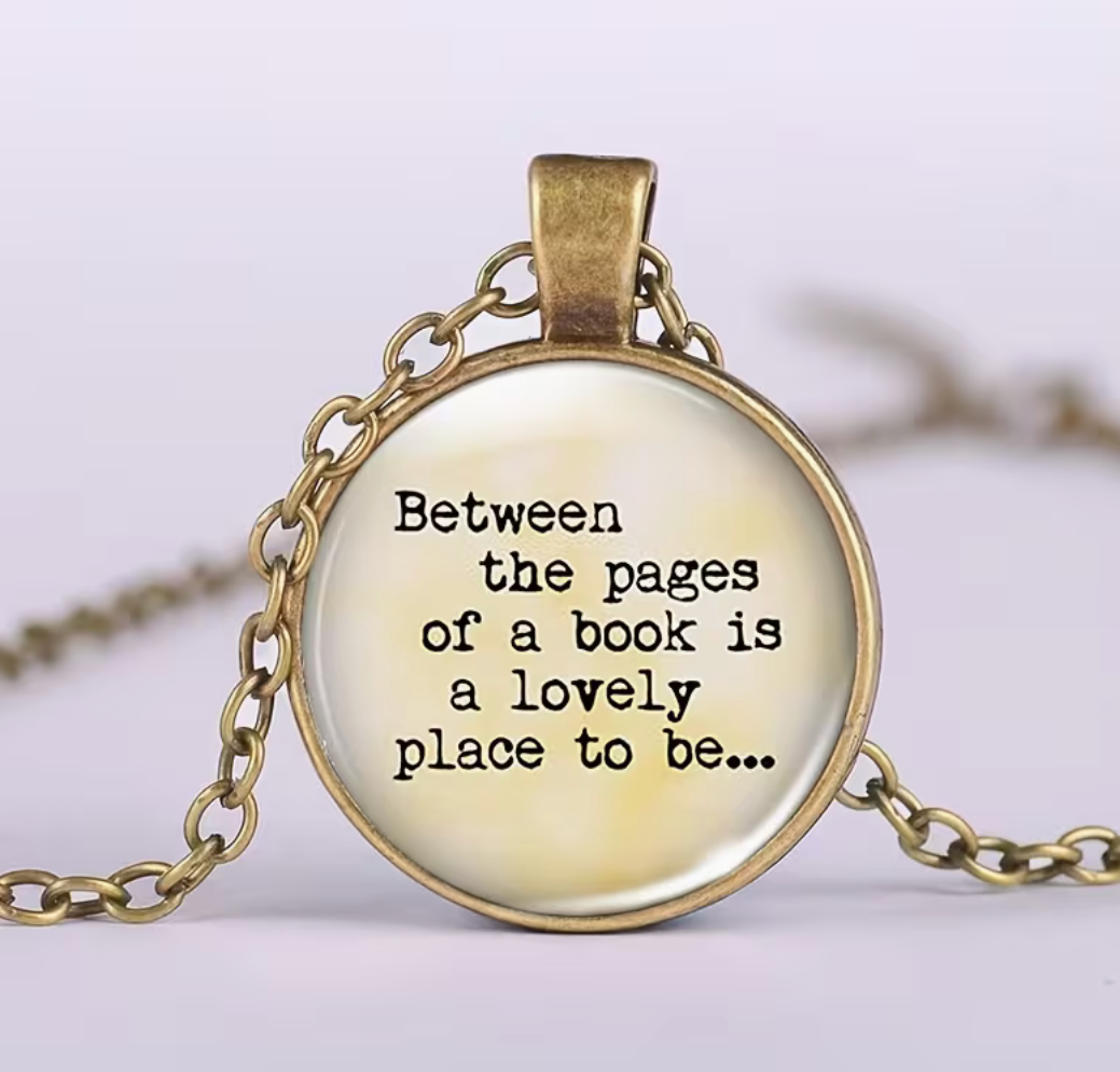 An antique bronze round pendant necklace featuring the quote 'Between the pages of a book is a lovely place to be.