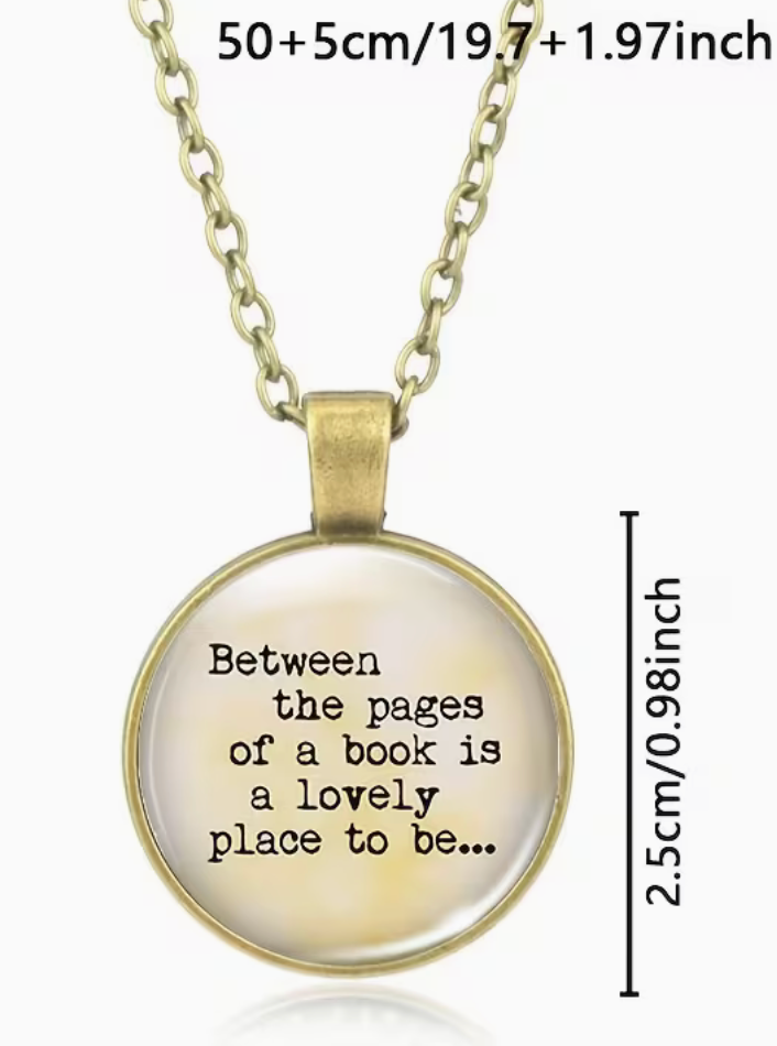 Gold-toned pendant necklace with a round glass dome showing the quote 'Between the pages of a book is a lovely place to be.