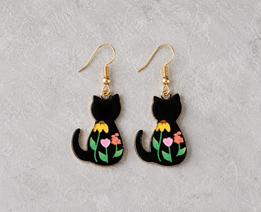 Black cat pendant earrings with colorful floral enamel details and gold-tone hooks on a neutral background