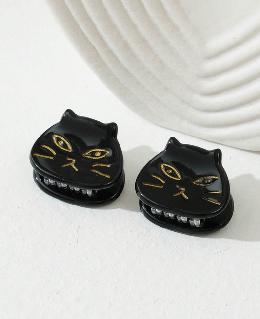 Black cat-shaped earrings with gold accents on a white surface