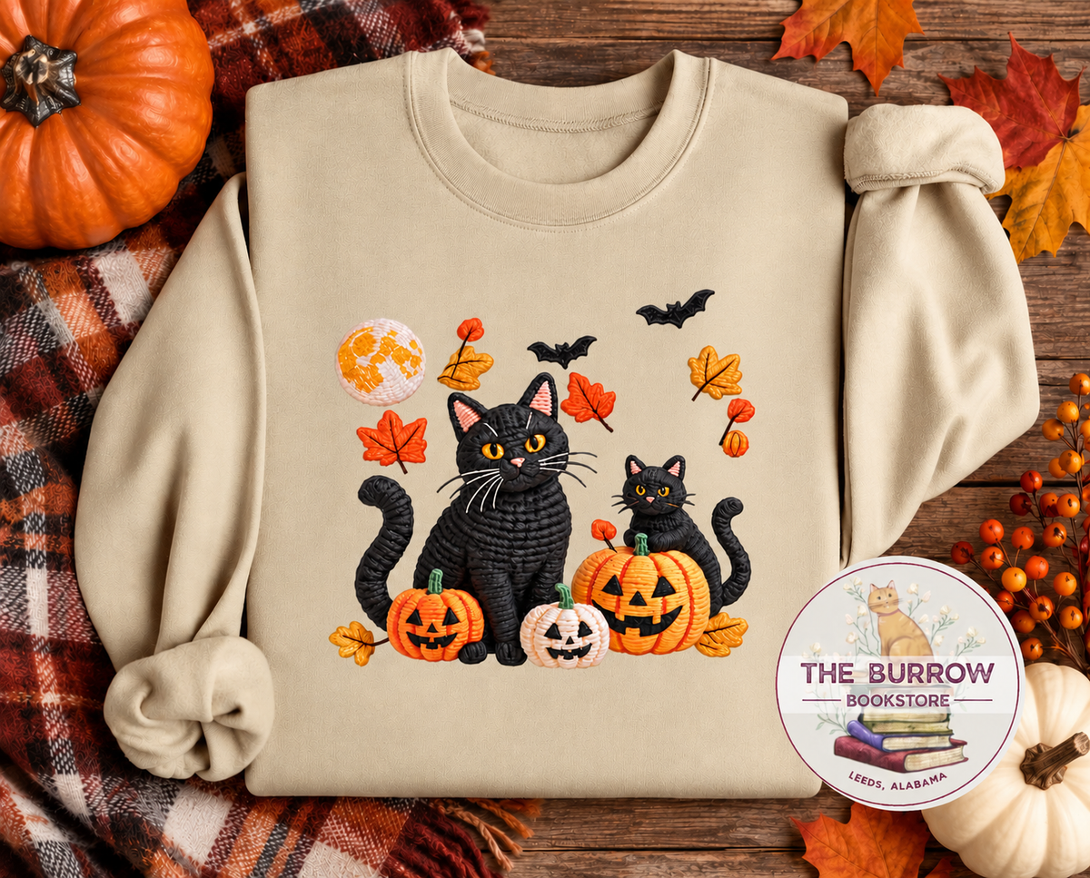 Black cats and pumpkins Halloween sweatshirt in sand with bats, autumn leaves and jack-o-lanterns