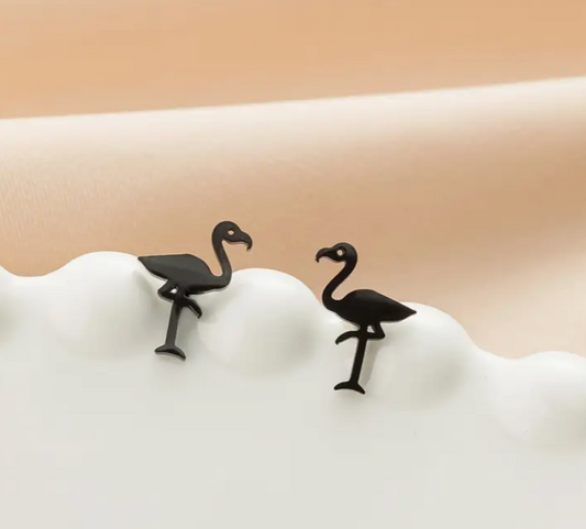 Black flamingo earrings on a white stand with a beige background