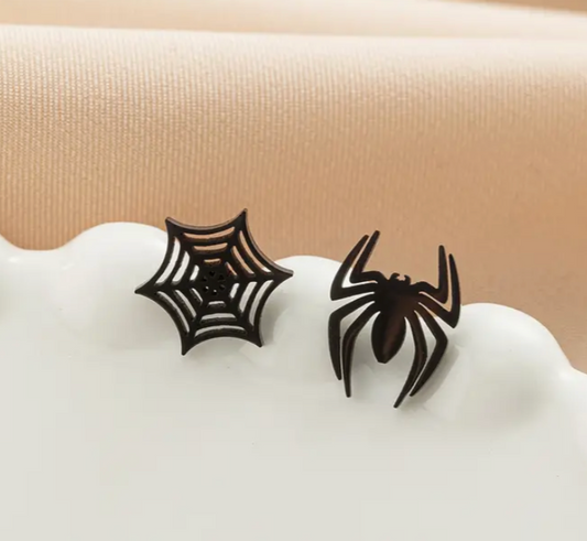 Black spider and web earrings on a white stand with a beige background