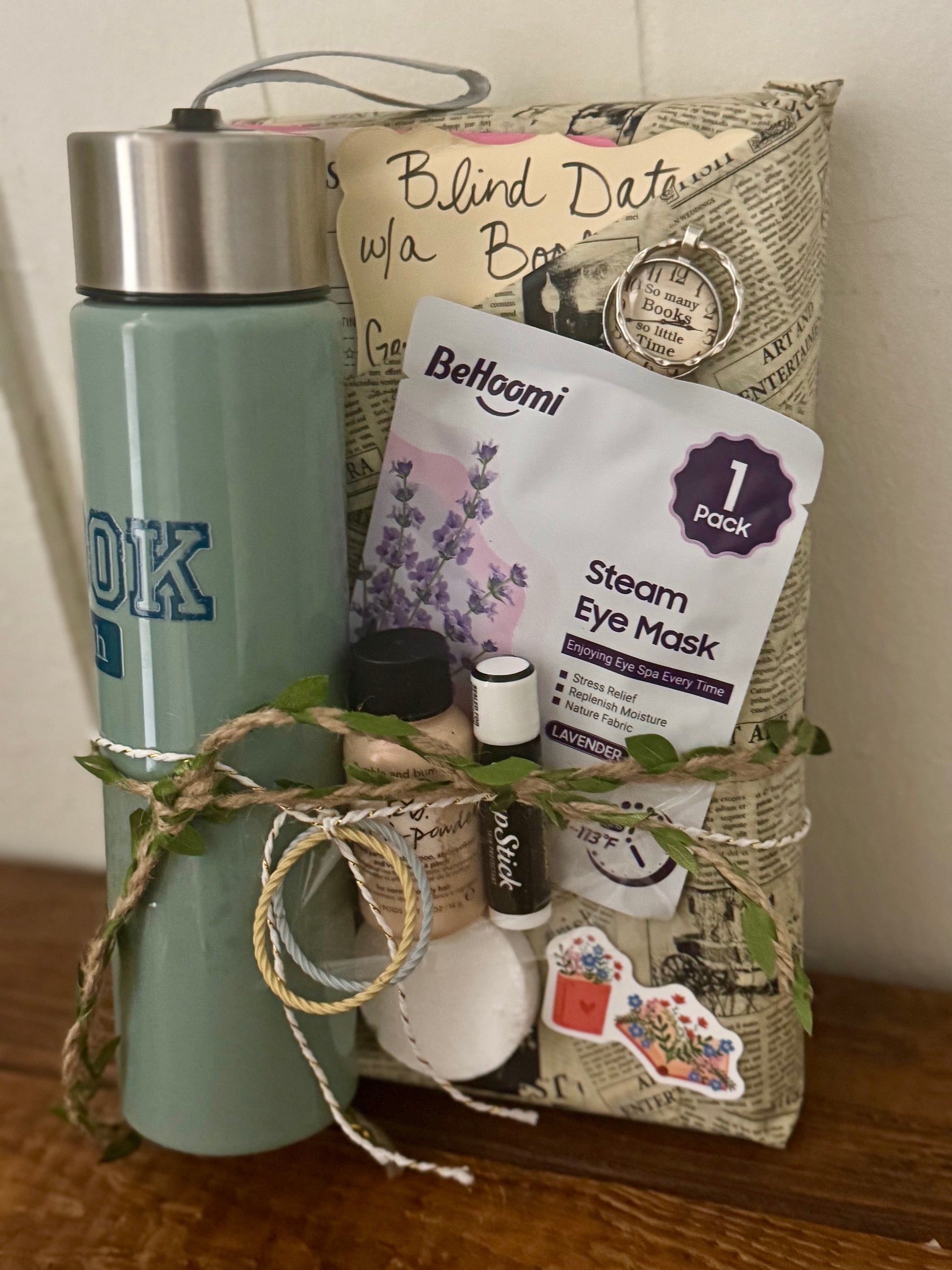 Gift basket with items including a water bottle, eye mask, and small bottles on a wooden surface.