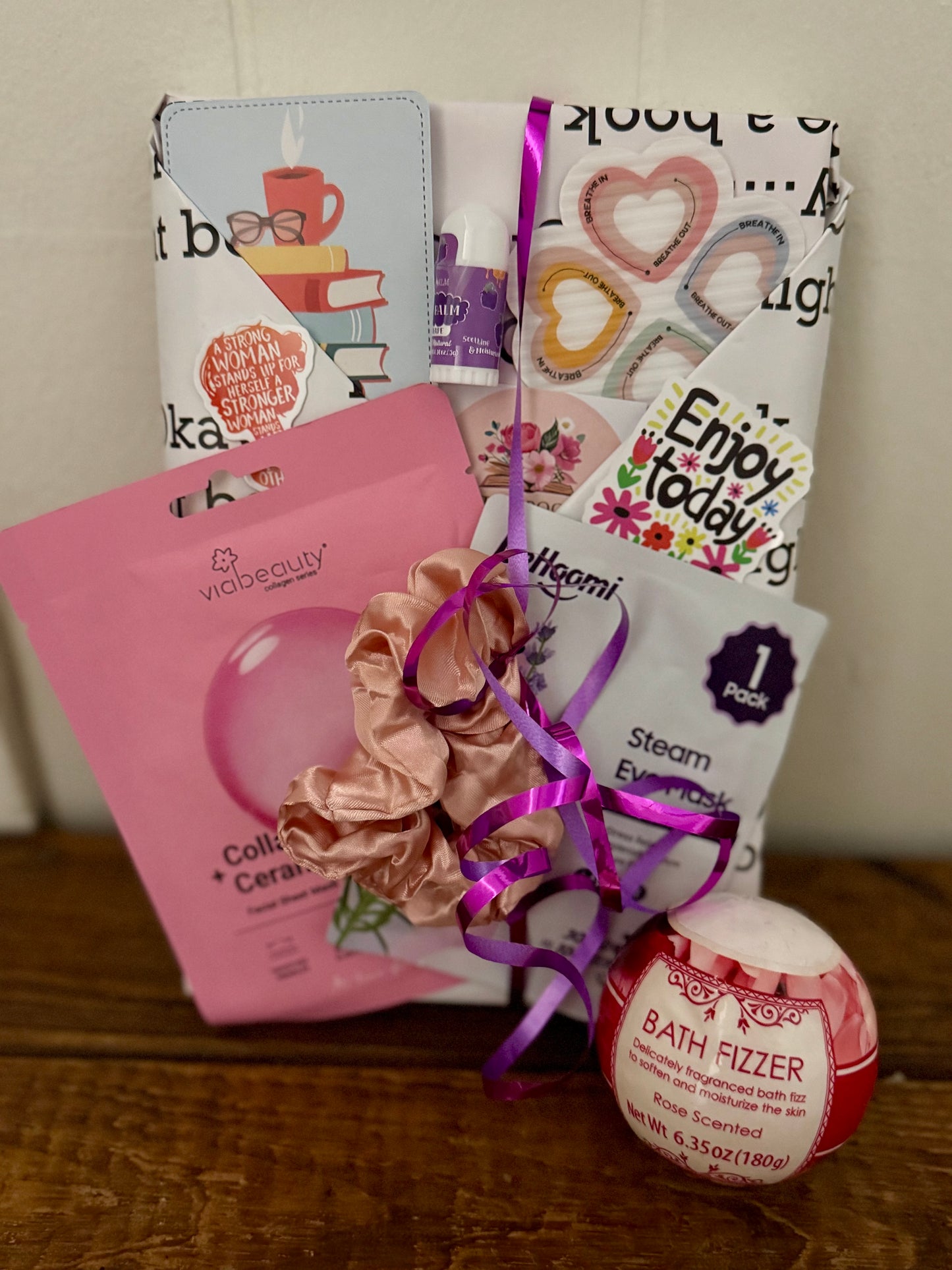 Collection of beauty products including a scrunchie, bath fizzer, and other items on a wooden surface.